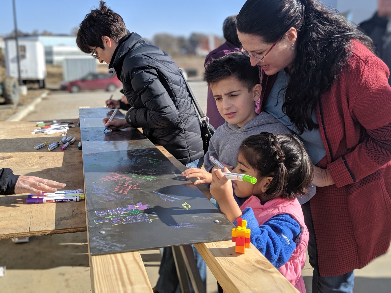 Mom and kids signing board